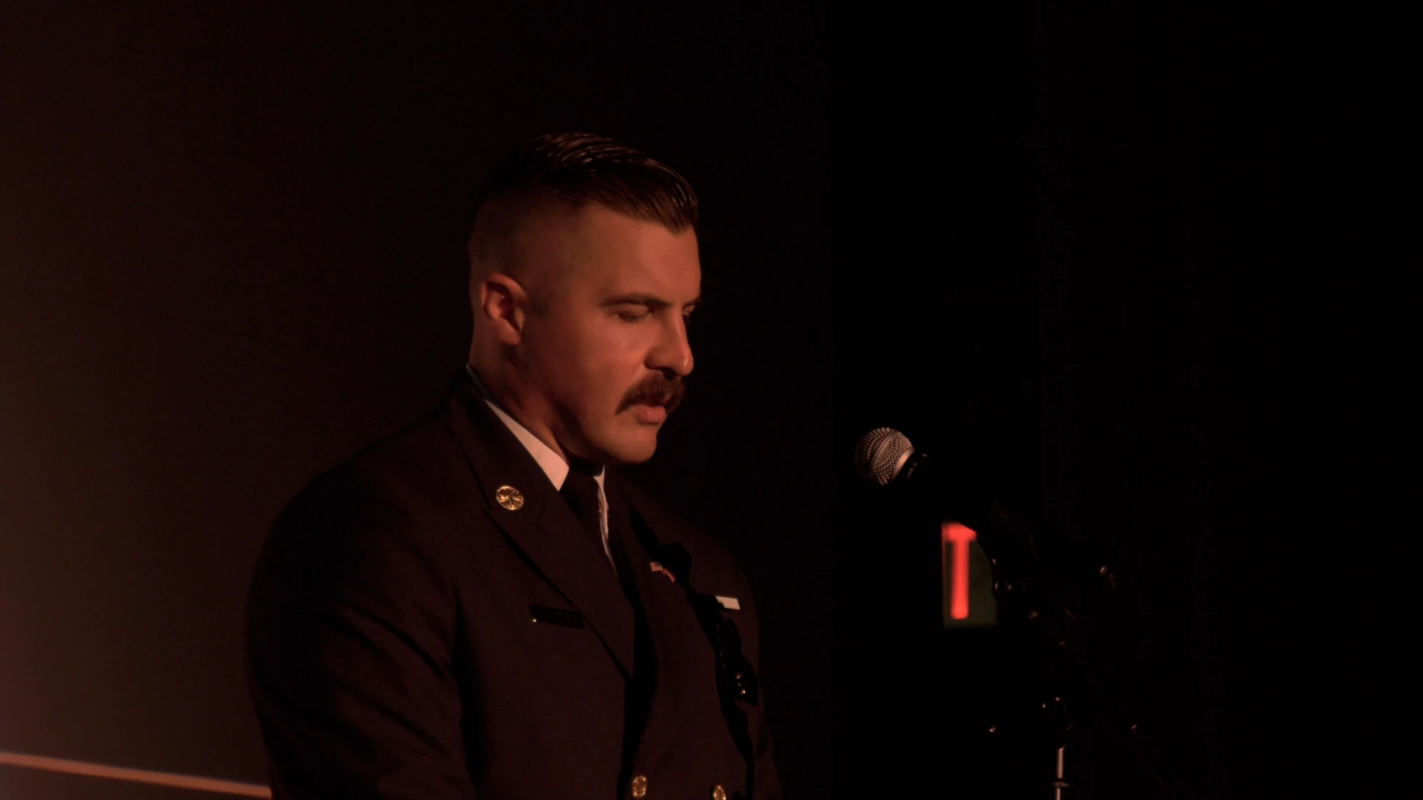 A firefighter in dress uniform speaks at a microphone
